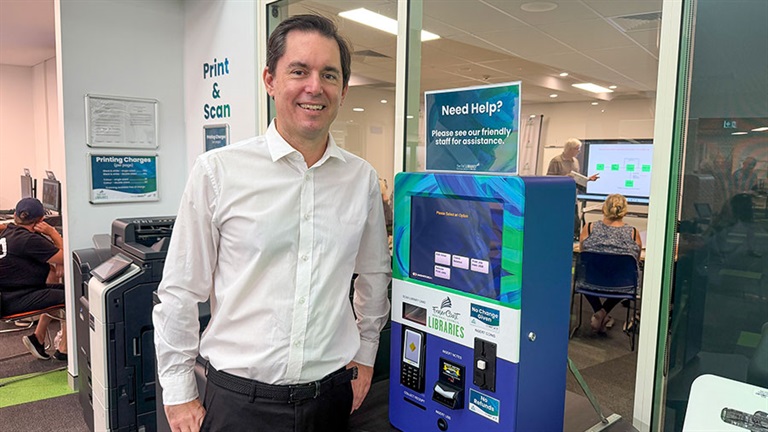 Mayor George Seymour standing next to an automated printing machine at the Hervey Bay Library