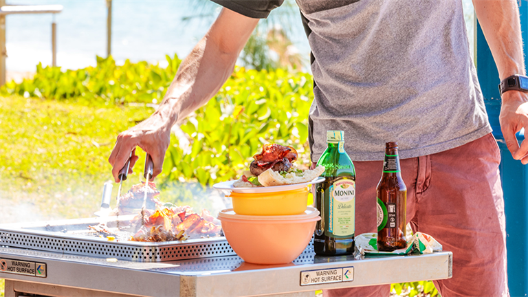 Person cooking on BBQ at park along Hervey Bay Esplanade