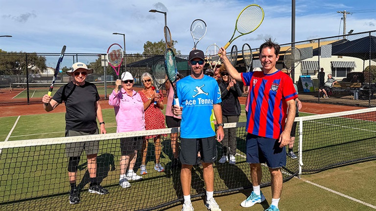 Group of people holding tennis racquets on court