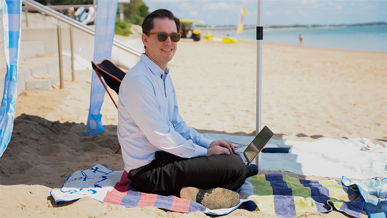 Mayor George Seymour working on laptop at Hervey Bay beach