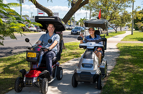 Mayor George Seymour and local resident riding in mobility scooter on footpath