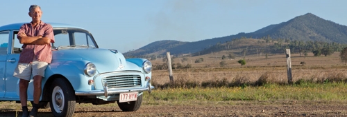 Man leaning on vintage car with Mt Bauple in background