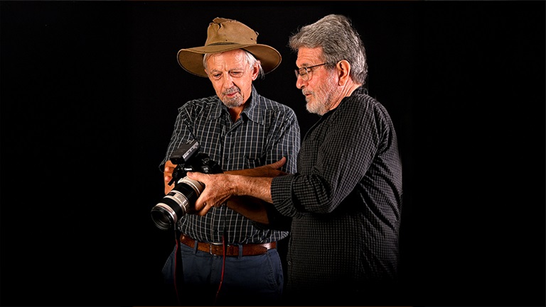People standing together, against a dark backdrop, looking at a digital camera.jpg
