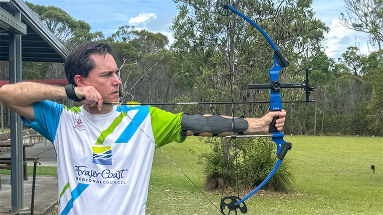 Mayor George Seymour aiming bow at target