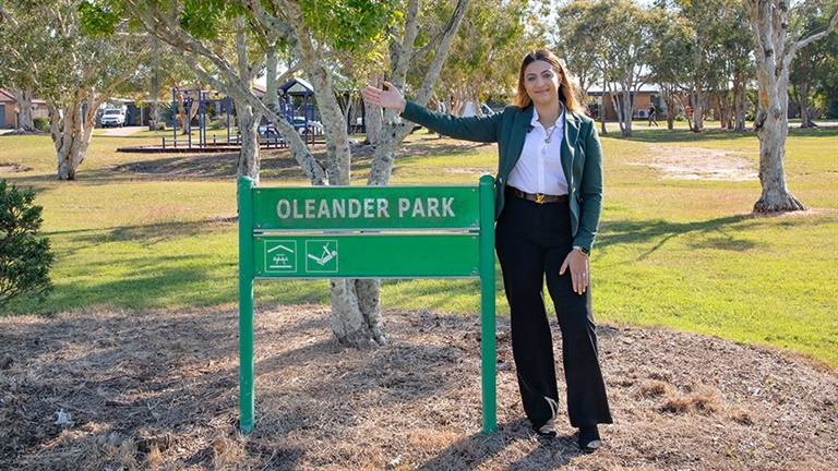 Cr Sara Diana Faraj standing next to sign at Oleander Park