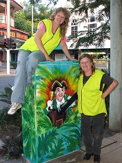 Artists posing next to Adelaide and Kent Street hand painted traffic box 