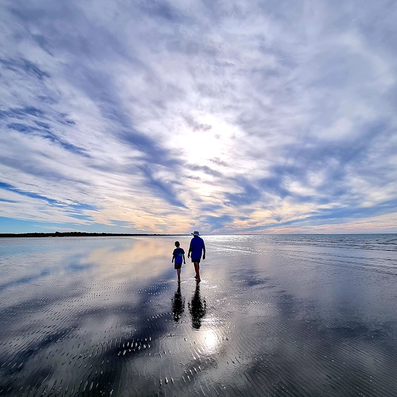A grandfather and grandson strolling along the beach